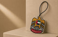 Decorative keychain with a shield design on a beige background