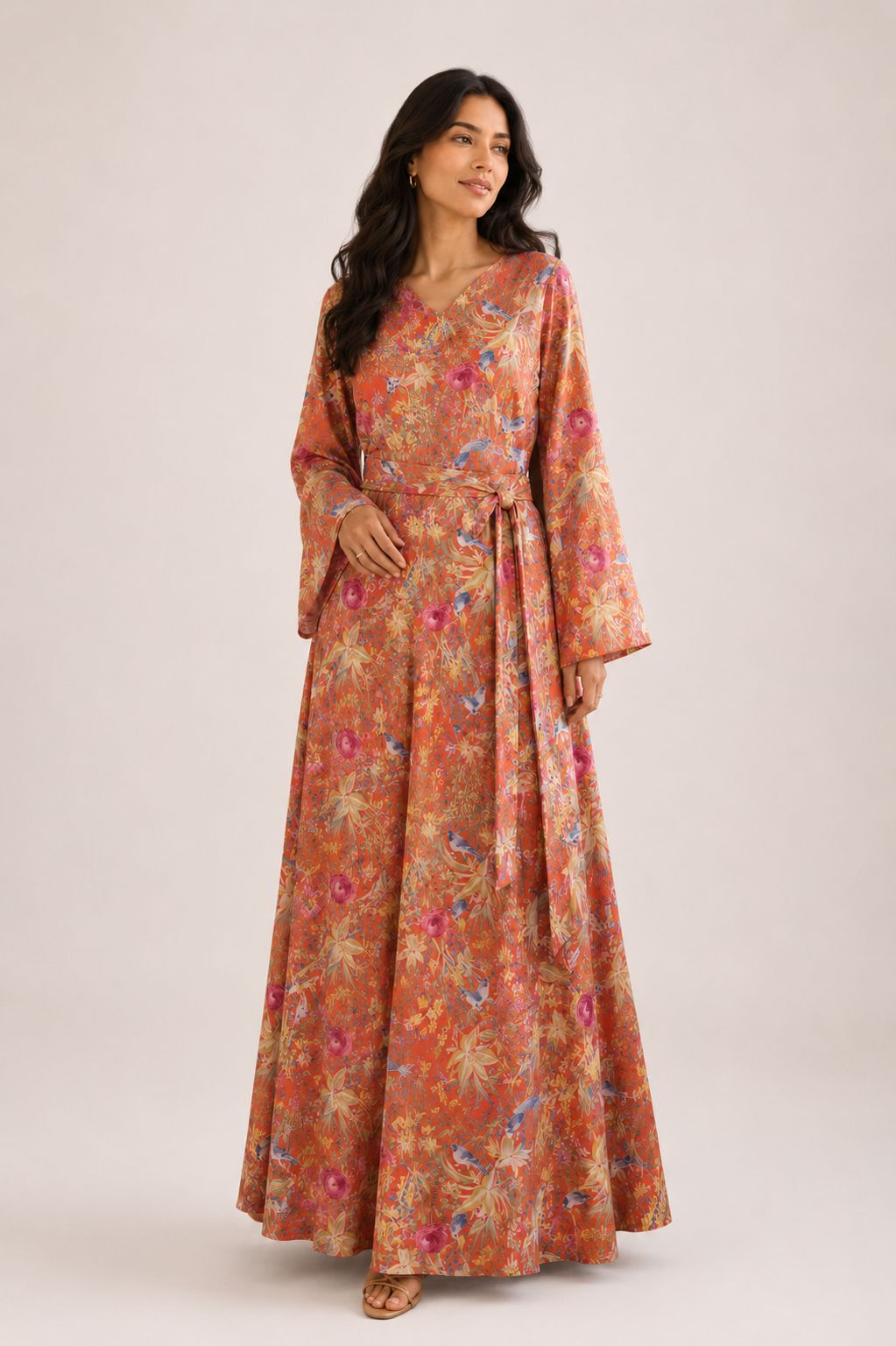 Woman wearing a floral  and birds dress with long sleeves on a white background