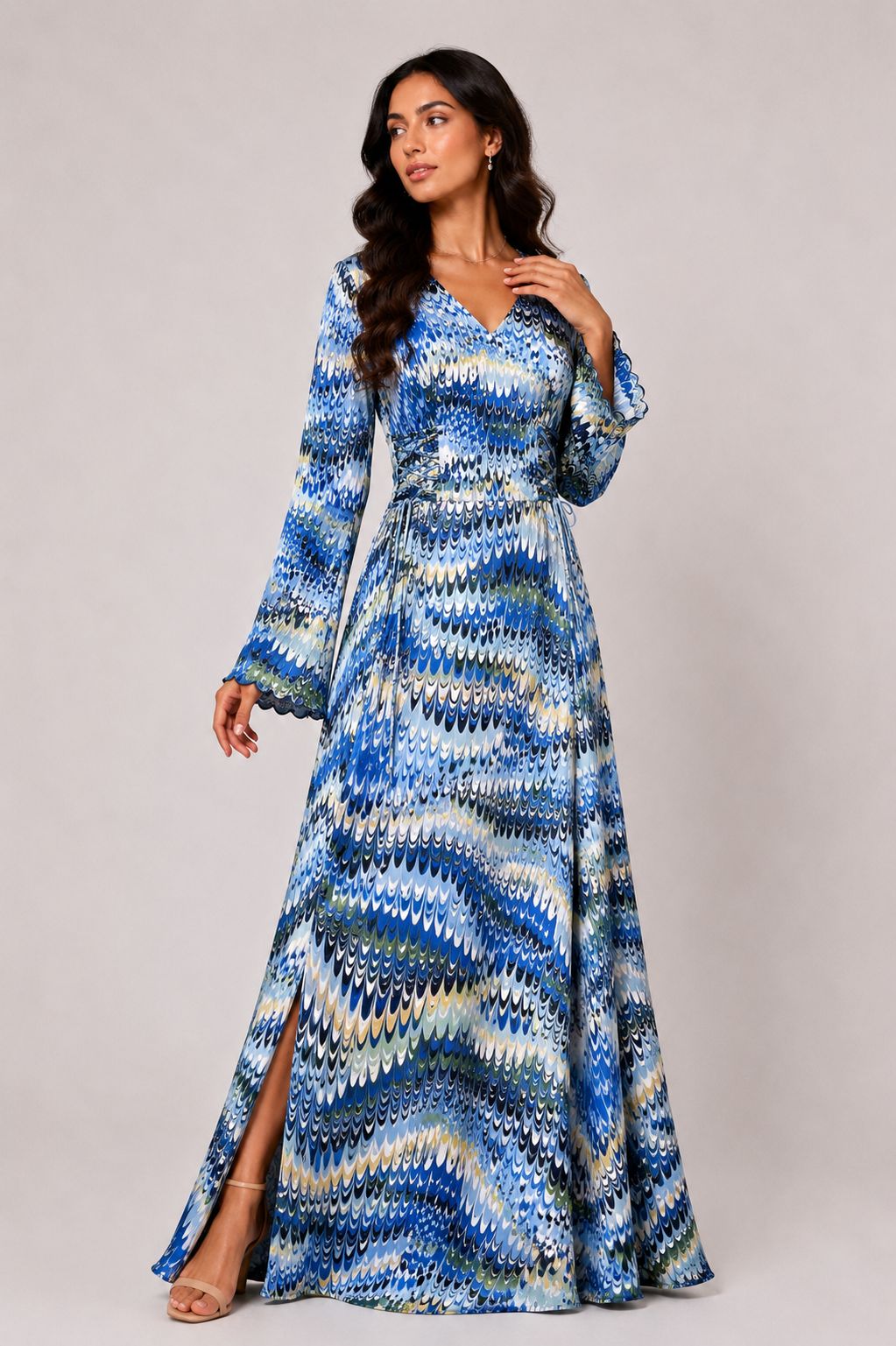Woman wearing a long, patterned blue dress against a plain background
