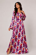 Woman wearing a long floral dress on a plain background