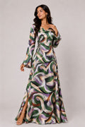 Woman wearing a long, patterned dress against a plain background