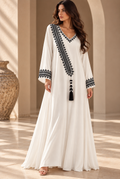 White full-length cotton dress with black hand embroidery, a V-neck, diagonal embroidered panel, long sleeves and tassel.
